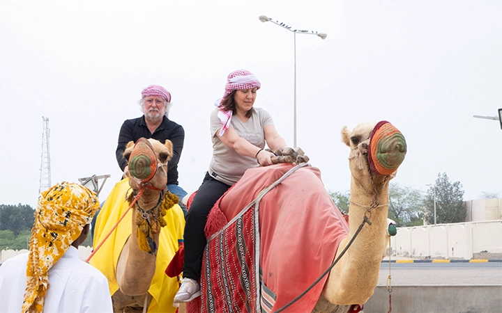 Tourists on camelback at desert safari Qatar