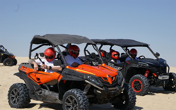 Tourists riding quad bikes in Qatar desert safari