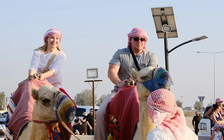 Tourists riding camels in Wild Dunes Desert Safari Qatar