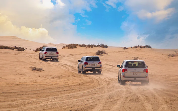 Cars driving across desert dunes at Wild Dunes Desert Safari Qatar